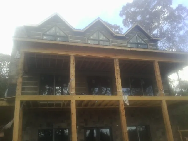 Dormers and porch framing on a large log home under construction — Roof Coating work by our crew in Rice